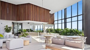A modern indoor lounge with a high ceiling, large windows, and a variety of seating arrangements including sofas and round tables. - CASSA CASINO - Spectacular River & Hinterland Views 1 Bed Apt in Broadbeach! (Broadbeach)