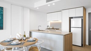 A modern kitchen with white cabinetry, a built-in island, and a stainless steel refrigerator.