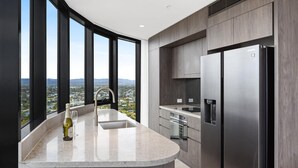 Una cocina moderna con una isla curva, electrodomésticos de acero inoxidable y vistas a un paisaje urbano.