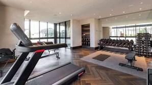 Un gimnasio con cinta de correr, mancuernas y un banco.