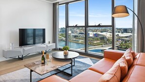 Una sala de estar moderna con un televisor grande, una mesa de centro redonda y un sofá.
