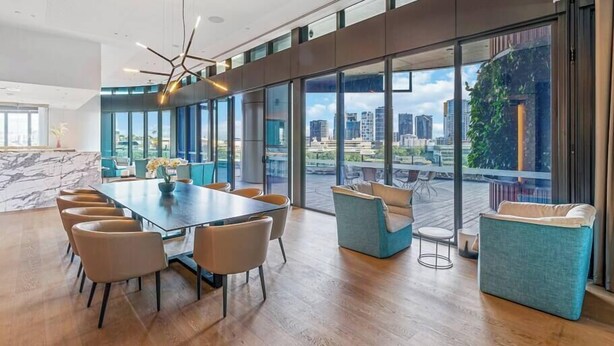 Un salón de conferencias moderno con una amplia mesa, asientos cómodos y ventanas grandes que ofrecen vistas a la ciudad.