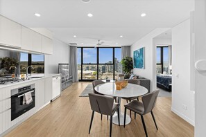Une cuisine moderne avec un coin repas, de grandes fenêtres et une vue sur la ville.