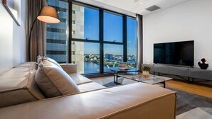 Una sala de estar moderna con un ventanal grande, un sofá, una mesita de centro y un televisor de pantalla plana.