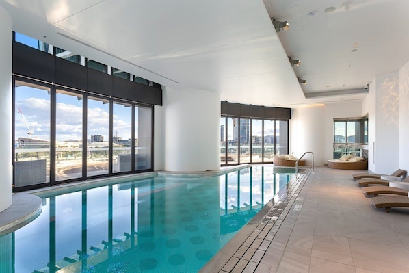 Relax by the pool with a city view, surrounded by lounge chairs and a seating area.