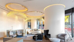 A modern lobby with a reception desk, seating area, and large windows.