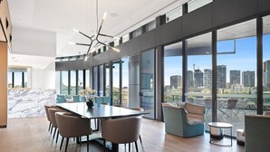 A modern conference room with a large table, comfortable seating, and large windows offering a city view.