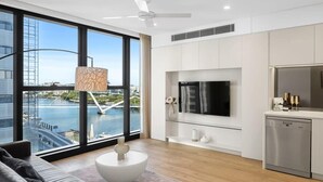 A modern living room with a large window, a flat-screen TV, a sofa, a coffee table, and a dishwasher.