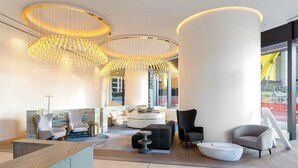 Eine moderne Lobby mit einer Rezeption, einer Sitzgelegenheit und großen Fenstern.