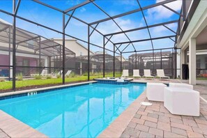 Une piscine entourée d’une structure en verre, de chaises longues et d’une terrasse en briques.