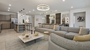 Ein modernes Wohnzimmer mit einem Ecksofa, einem Couchtisch und Pendelleuchten.