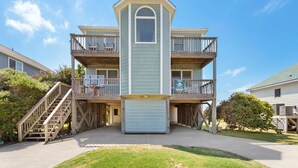 A multi-story building with a central tower, balconies, and a staircase leading to the entrance. - 7074 Seashells and Sunsets * 3 Min Walk to Beach (Nags Head)