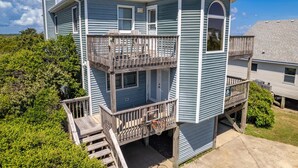A two-story house with a balcony, a front door, and a small porch area. - 7074 Seashells and Sunsets * 3 Min Walk to Beach (Nags Head)