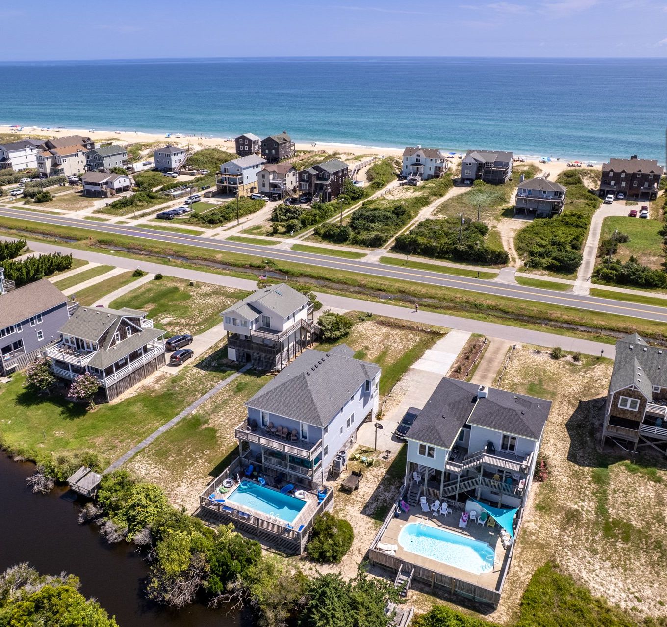 A residential area with houses, a swimming pool, and a beach access point.