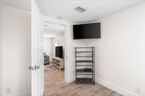 Enter a spacious living area with a flat-screen TV and shelving unit.