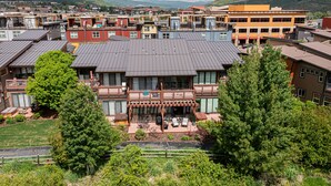 Um edifício moderno de vários andares com telhado plano, grandes janelas e área externa coberta com assentos.
