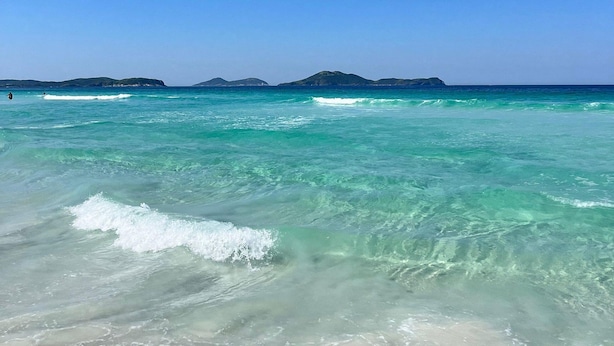 A beach with clear turquoise water, distant islands, and a clear sky. - Confortável Apto na Praia do Forte (Cabo Frio)