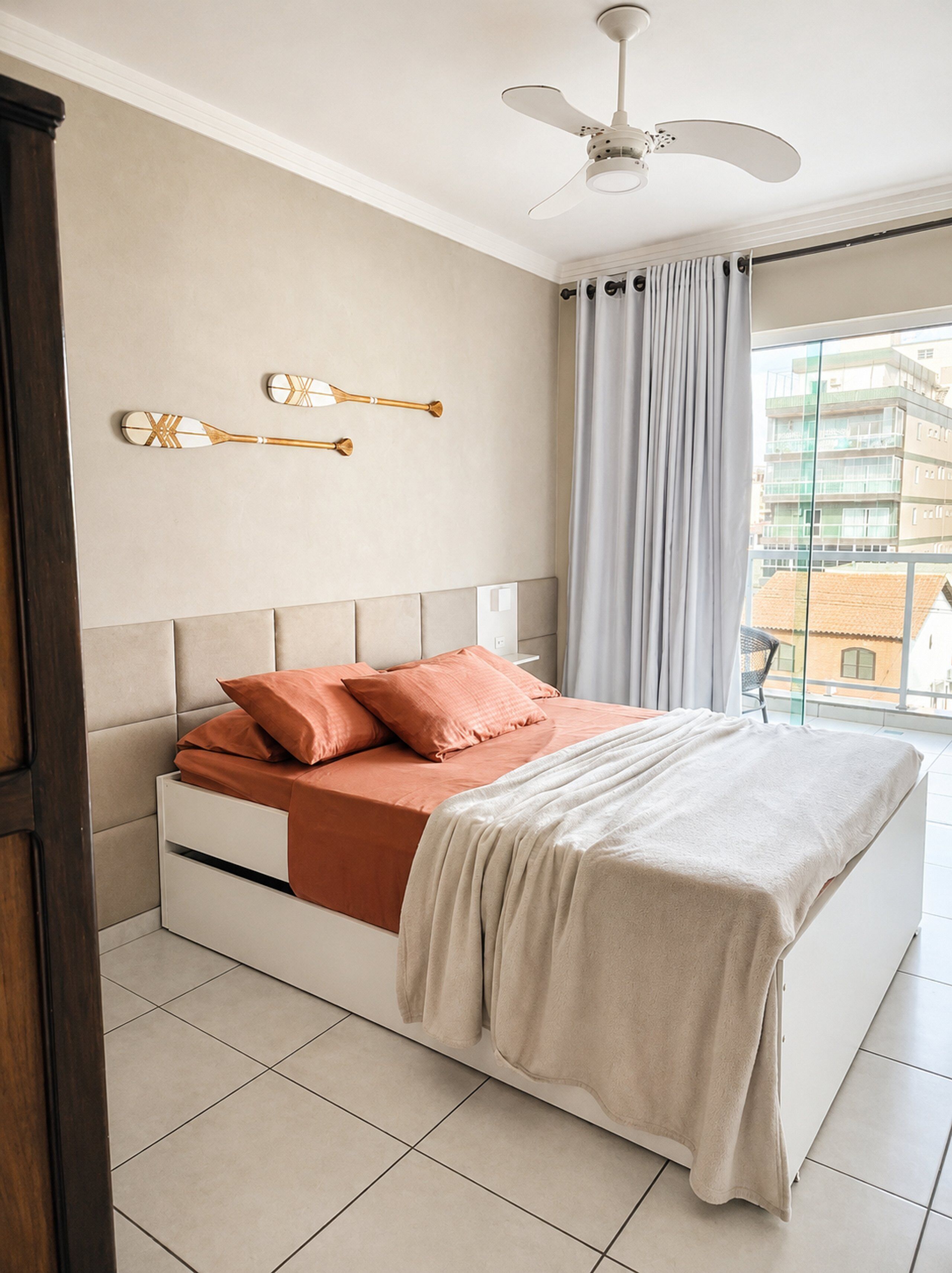 A bedroom with a bed, pillows, a ceiling fan, and a window with curtains.