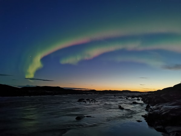 A river at dusk with a colorful aurora display above. - Grant's Arctic Escape (Iqaluit)