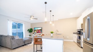 Cozinha moderna com ilha central, eletrodomésticos de aço inoxidável e iluminação pendente.