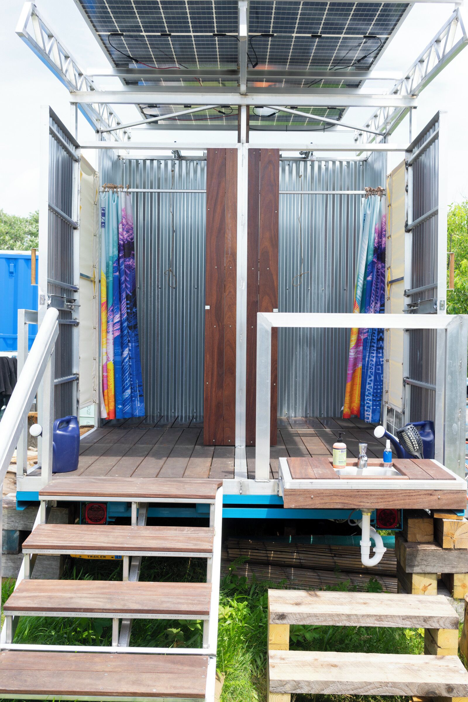 Un espace compact à plan ouvert, doté d’une terrasse en bois, de rampes en métal et d’un toit équipé de panneaux solaires.