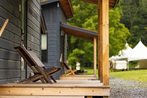 A wooden deck with a bench and a table, leading to a building with a dark exterior. - Madbush Falls (Waitsfield)