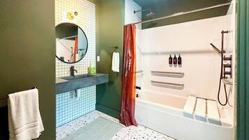 A modern bathroom with a bathtub, a shower, a sink with a mirror, and a towel rack.