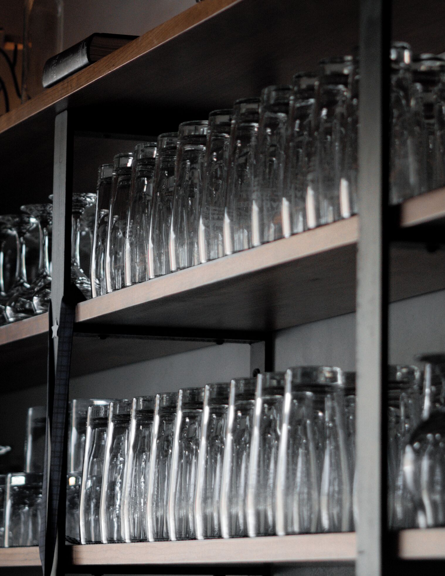 A shelf with multiple rows of clear glass bottles.