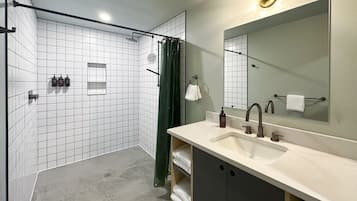 Un baño moderno con ducha, lavamanos, espejo y toallero.