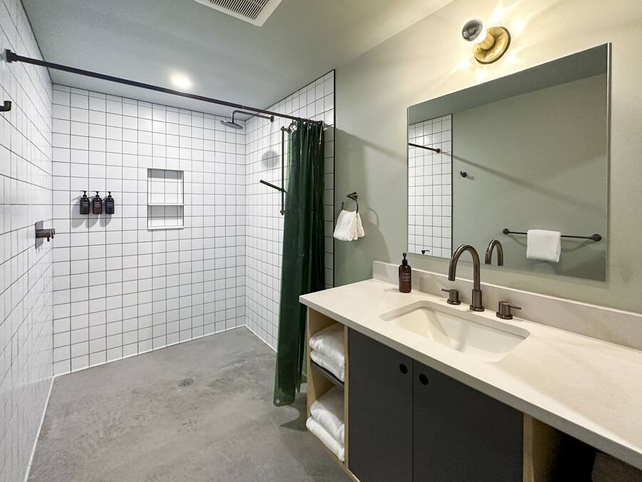 Un baño moderno con ducha, lavamanos, espejo y toallero.