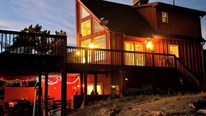 A two-story wooden house with a balcony, a satellite dish, and a gravel driveway.