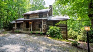 A rustic log cabin with a porch, stone foundation, and a gravel driveway. - Charming Cabin Near Blue Ridge Mountains (Blowing Rock)