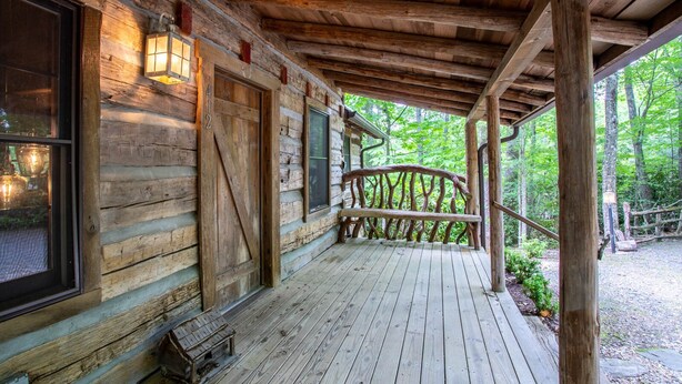 A wooden cabin with a porch, large windows, and a wooden staircase leading to a deck. - Charming Cabin Near Blue Ridge Mountains (Blowing Rock)
