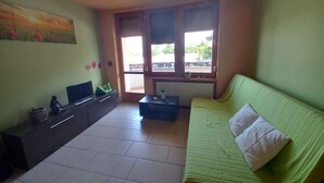 A room with a bed, a desk, a chair, a TV, and a window. - Holiday apartment with air conditioning, in the pedestrian zone (Balatonlelle)