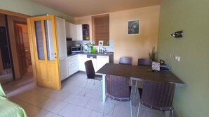A compact kitchen with modern appliances, a dining area with a table and chairs, and a small living space with a bed. - Holiday apartment with air conditioning, in the pedestrian zone (Balatonlelle)