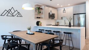 Una cocina moderna con una mesa de comedor de madera, taburetes negros y una isla blanca.