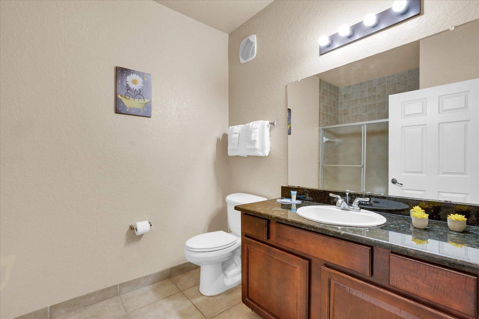 A bathroom with a toilet, sink, vanity, and a large mirror.