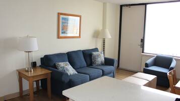 A living room with a sofa, a small table, a chair, and a lamp.
