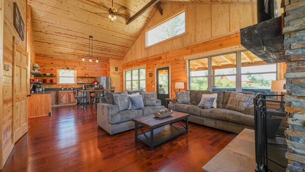 A spacious living area with wooden floors, a large sofa set, and a fireplace. - Bourbon Trail Lodge by The Inn & Spa at Cedar Falls (Logan)