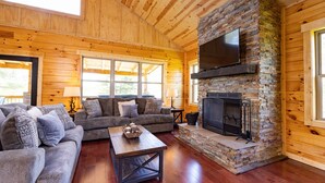 A cozy cabin interior with a stone fireplace, wooden walls, and a comfortable seating area. - Bourbon Trail Lodge by The Inn & Spa at Cedar Falls (Logan)