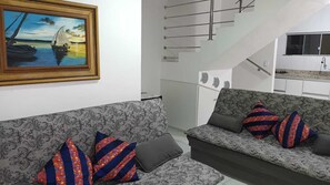 Relax in this stylish living room with a sofa set, framed artwork, and a staircase.