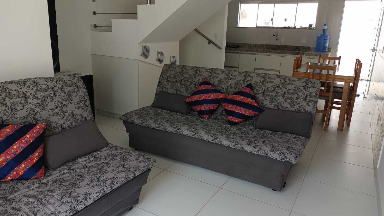 A living room with a sofa and a chair, a staircase, and a kitchen area.
