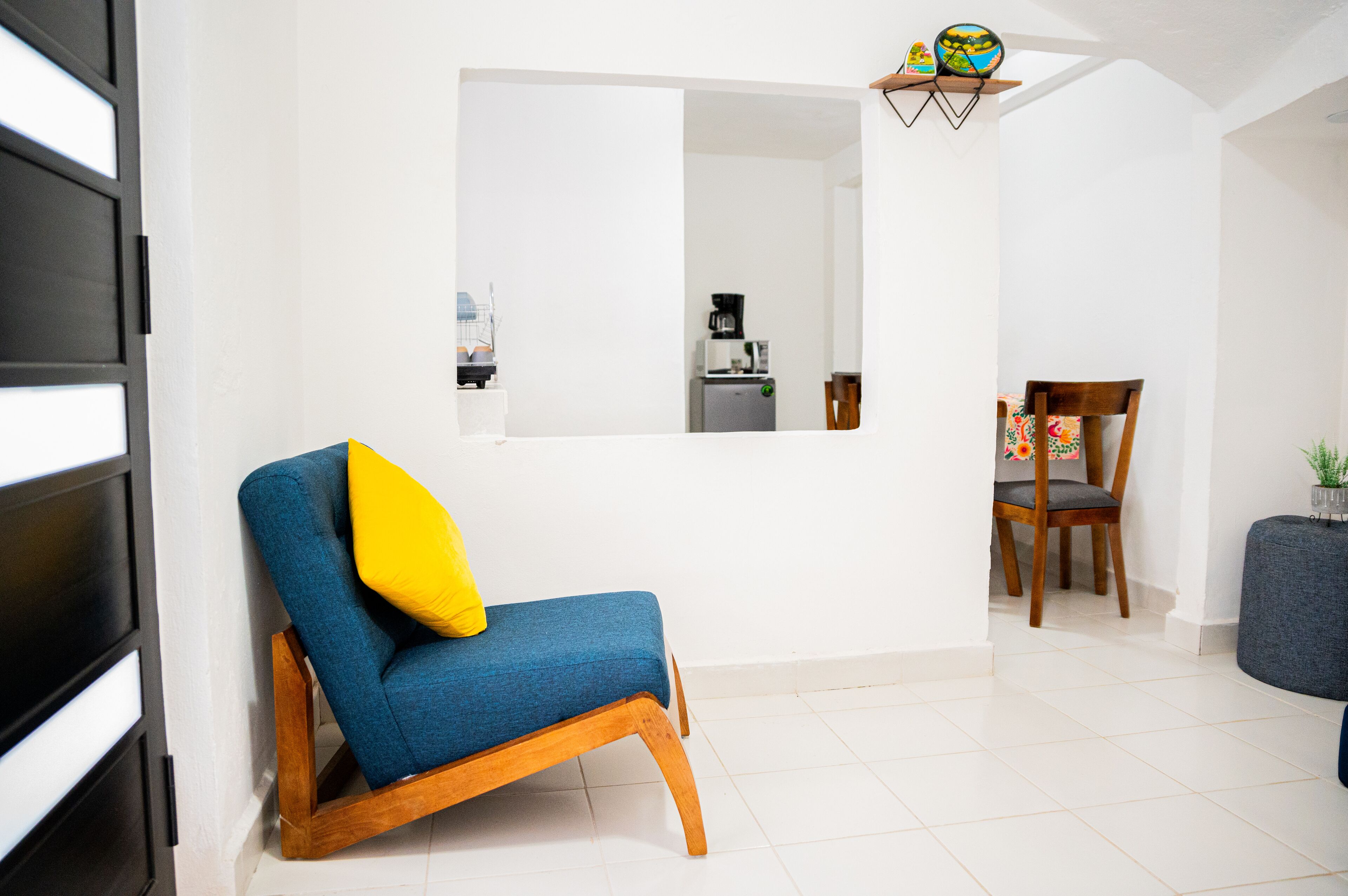 A modern living room with a blue sofa, a wooden chair, and a small table.