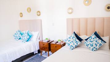 Habitación de hotel con dos camas, cada una con cabecera, y una mesita de noche entre ellas. Se observan espejos decorativos en la pared sobre las camas.