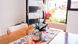 A dining table with a colorful placemat, a salt shaker, a pepper shaker, and a potted plant with white flowers. - HOTEL BUNGALOWS CASA BLANCA (Tenancingo)