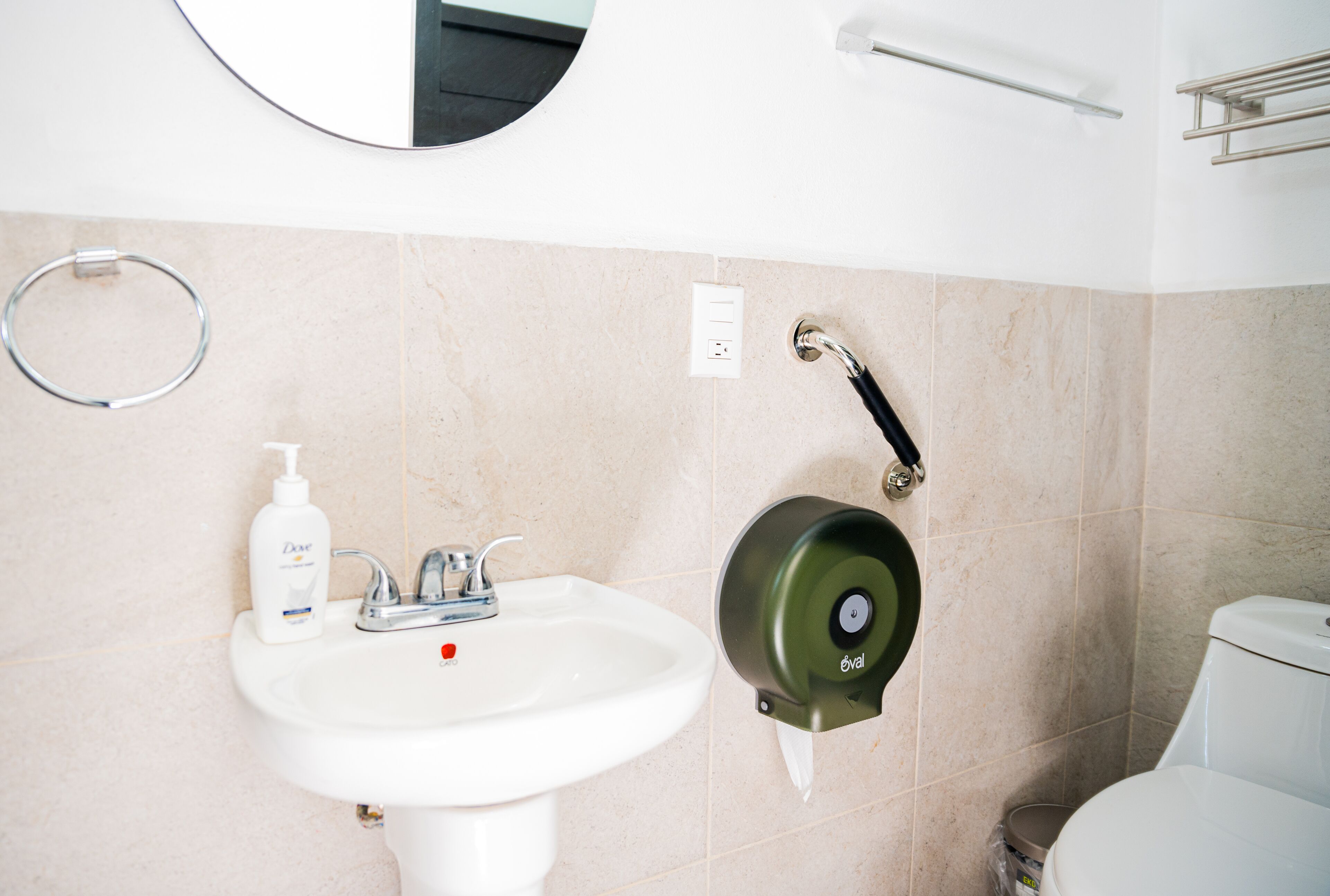 Une salle de bain avec un lavabo blanc, un miroir, un porte-serviettes et des toilettes.