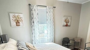 A bedroom with a bed, pillows, a bedside table, a chair, and a small table. - Walking Distance to Casino (Danvilel)