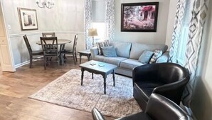 A living room with a sofa, coffee table, and a dining table with chairs. - Walking Distance to Casino (Danvilel)