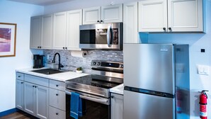 A modern kitchen with stainless steel appliances, white cabinetry, and a wooden floor. - Hyland Hotel (Palmer)
