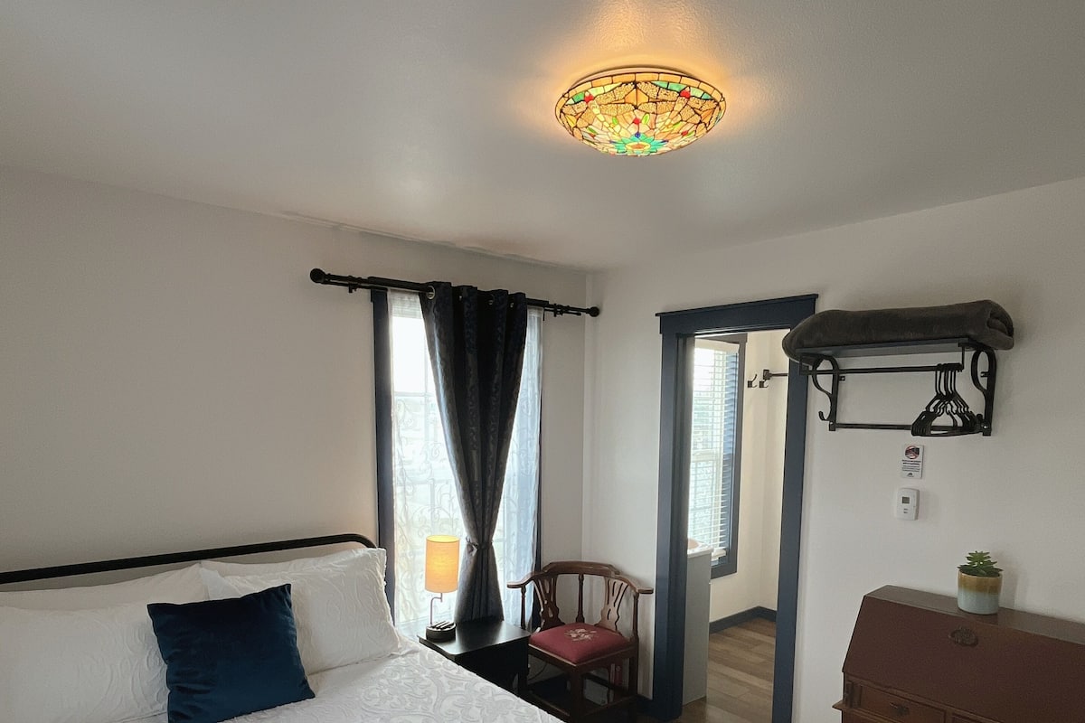 Hotellihuone, jossa on suuri sänky, työpöytä, tuoli ja pieni pöytä.